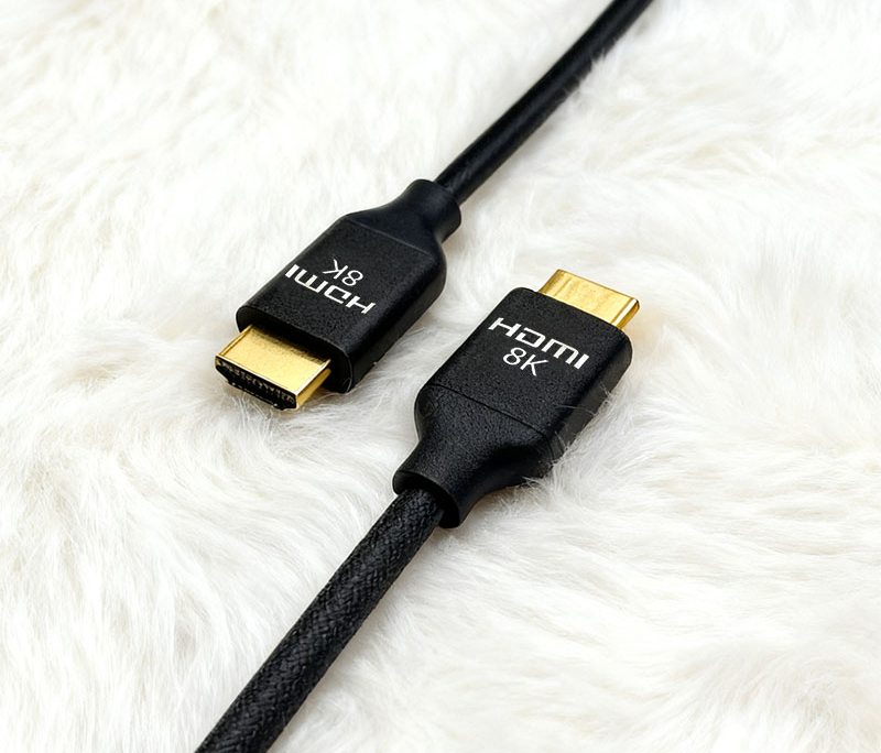 Black HDMI 8K Cable with Gold-Plated Connectors on White Wool Surface