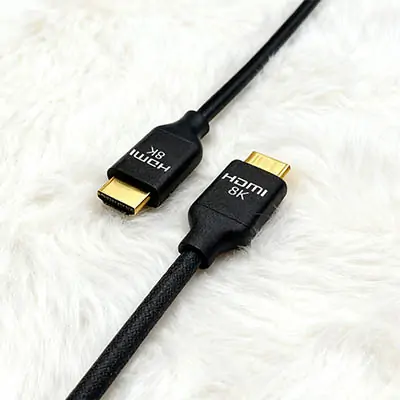 Black HDMI 8K Cable with Gold-Plated Connectors on White Wool Surface